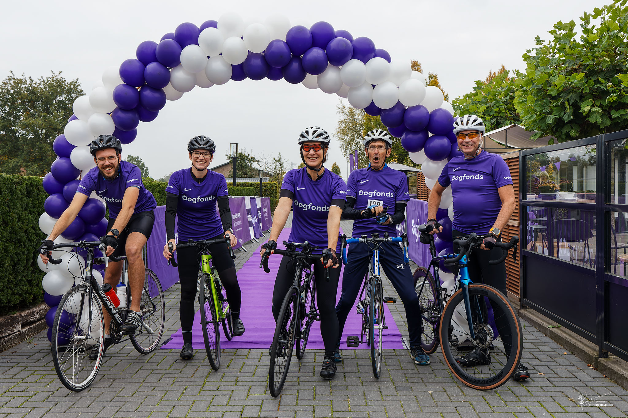Groep fietsers bij de Walk&Ride, onder de start boog van ballonnen.