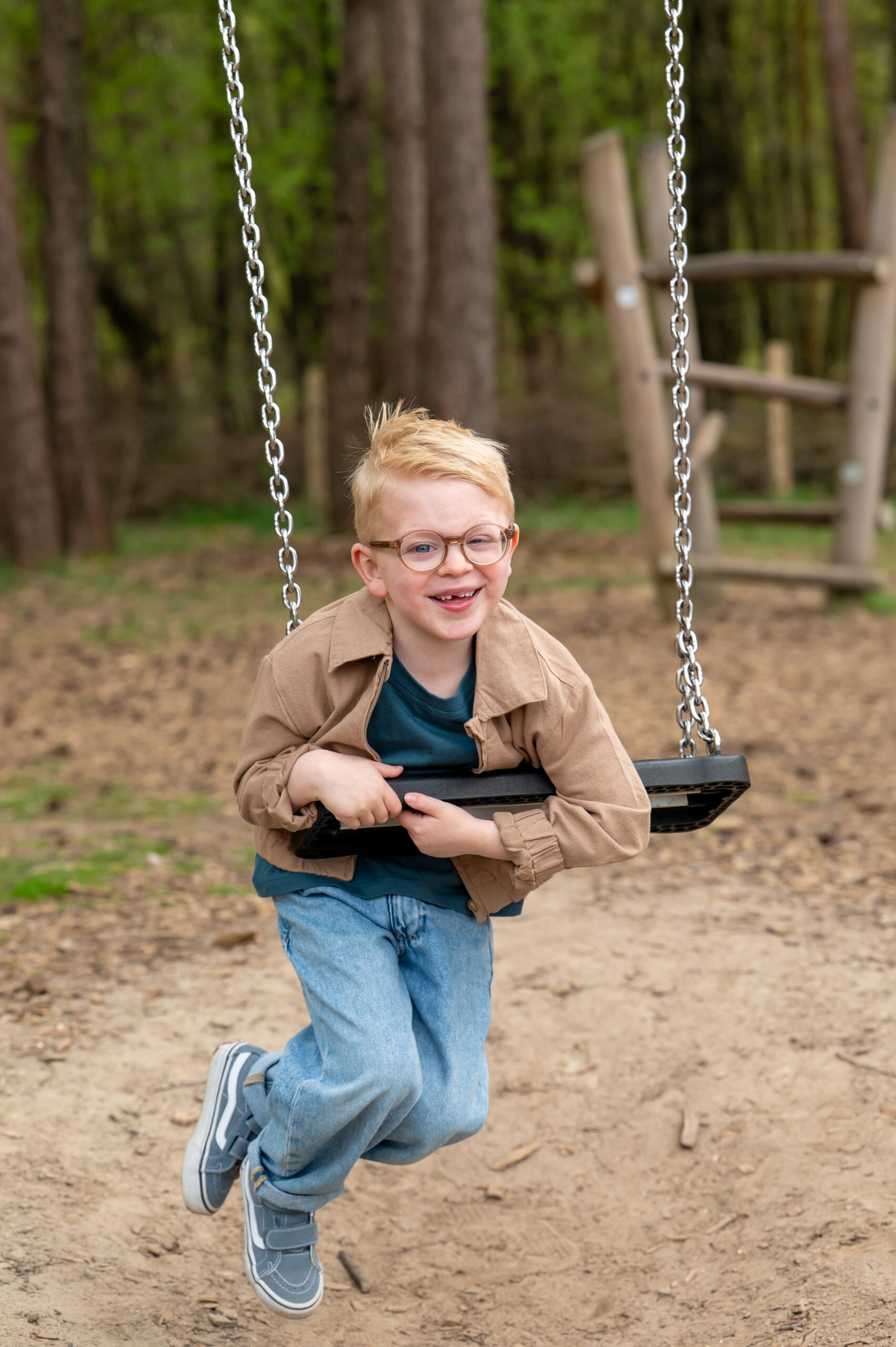 Joa (kinderglaucoom) hangt lachend aan een schommel