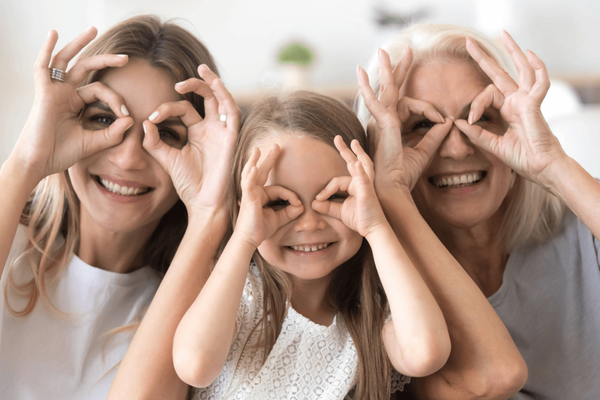 Drie generaties vrouwen doen handen in vorm van bril voor ogen