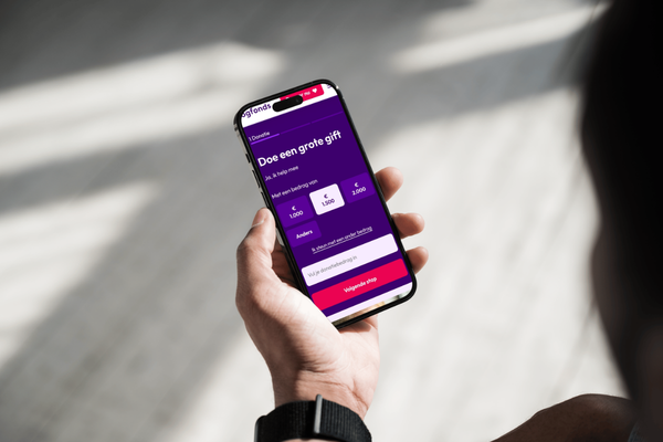 Close-up van hand die telefoon vasthoudt om zelf gift over te maken naar Oogfonds.